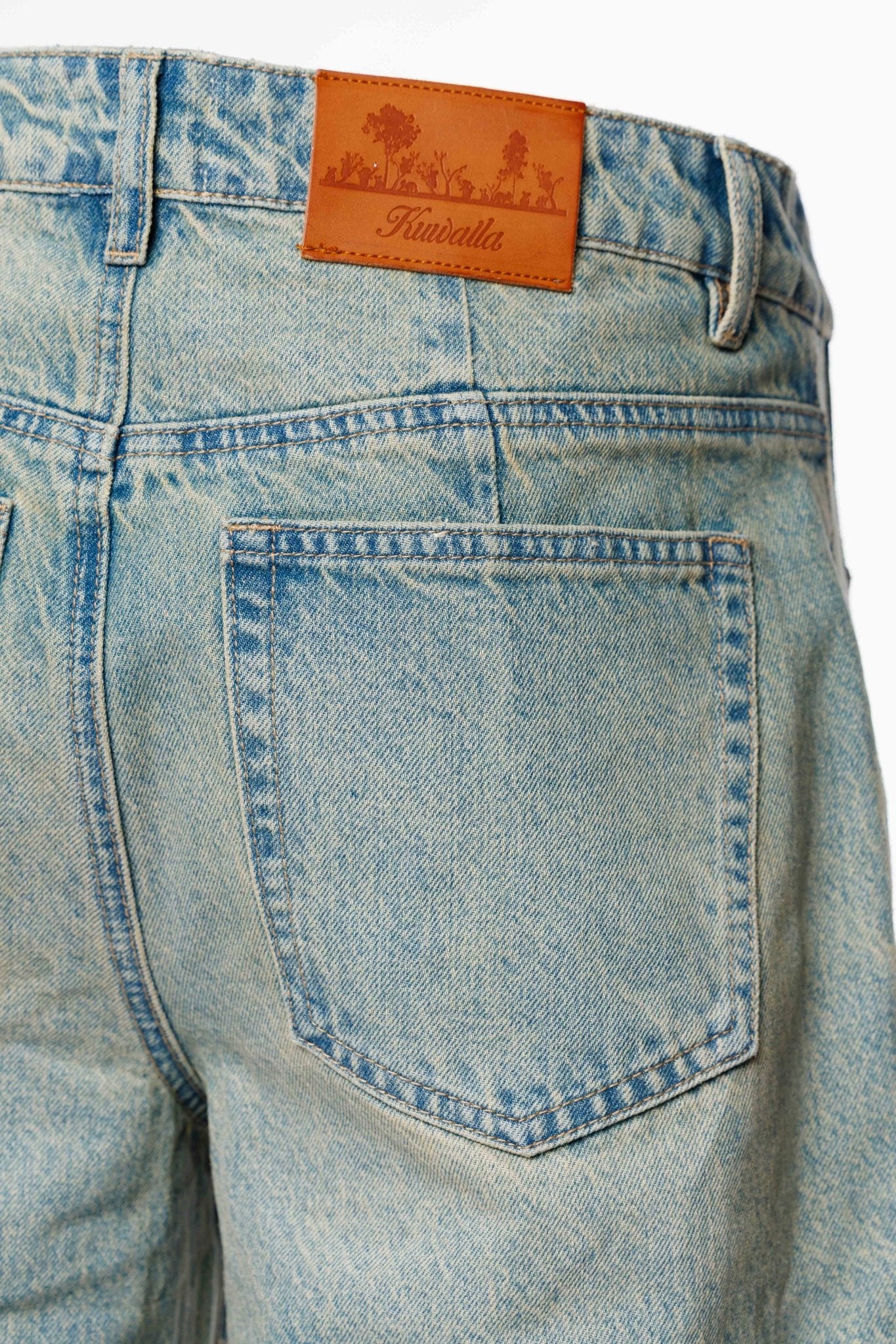 Close-up of a pair of blue jeans with a brand label on the back pocket.